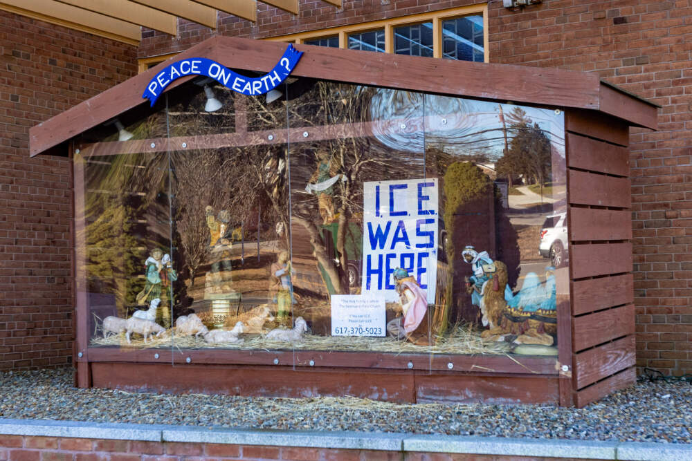 The annual nativity at St. Susanna’s Parish replaces the religious figurines with an “ICE Was Here” sign on Dec. 12. Below the display, reads another sign that says, “The Holy Family is safe in our Church ... If you see ICE please call LUCE at 617-370-5023.” (Jesse Costa/WBUR)